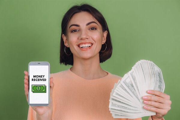 mujer que muestra el dinero recibido en una transferencia móvil