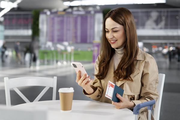 Smiling traveler holding passport and checking reservation details