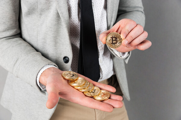 Man holding crypto coins to use at Bitcoin ATM