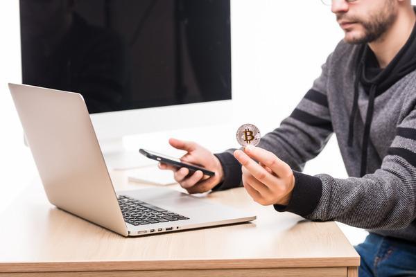 Un hombre verifica una transacción de Bitcoin en un cajero automático usando una computadora portátil.