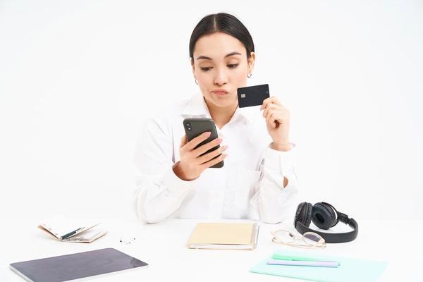 Mujer joven que verifica los detalles de una transferencia electrónica de dinero en su teléfono inteligente