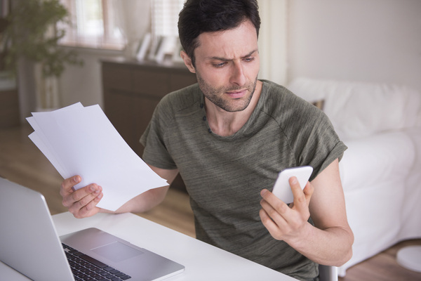 Frustrated man checking his phone about a delayed international money transfer