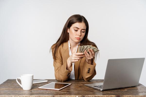 Sad businesswoman counting money after transfer mistake