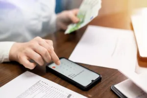 Persona que usa el teléfono para calcular transferencias de dinero