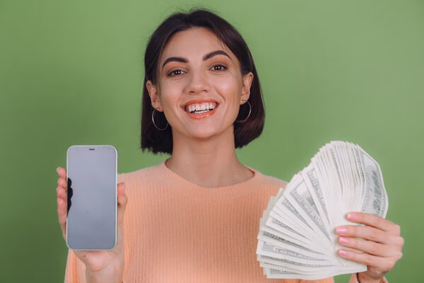 Una mujer sosteniendo un teléfono y dinero.