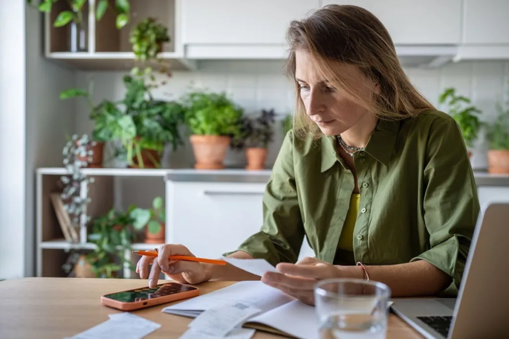 A woman calculating bill payments at home.