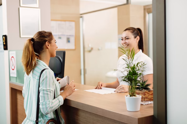 Smiling receptionist assisting customer with check cashing
