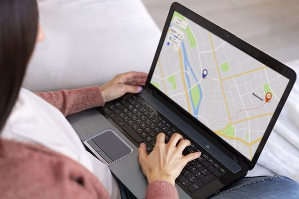 Una mujer utiliza el seguimiento de mapas de servicios de mensajería en su computadora portátil.