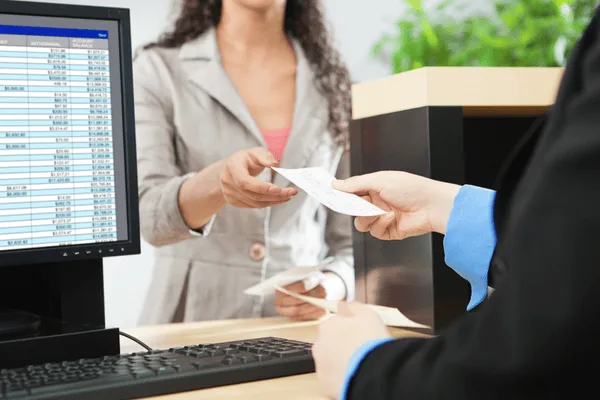 Teller handing check to customer at counter