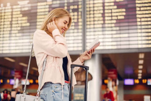 Una mujer joven comprueba los detalles de su billete en el panel de salidas del aeropuerto.