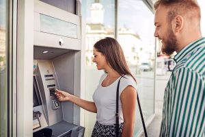 Woman using a Bitcoin ATM while man waiting in line.