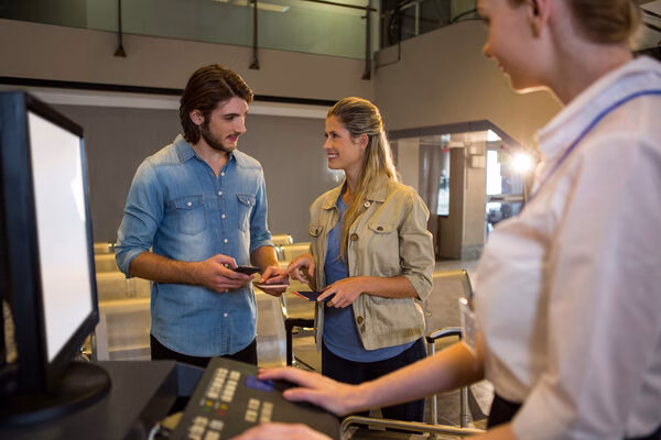 Pareja reservando billetes de avión en el mostrador del aeropuerto