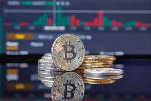 Stacked Bitcoin Coins in Front of Trading Chart