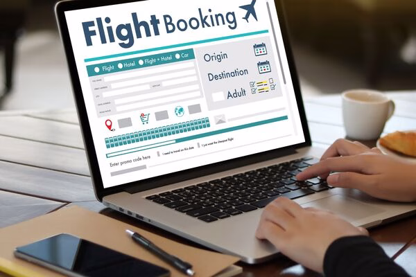Hands typing on laptop to search plane tickets online.
