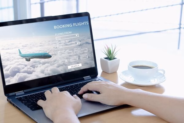 Persona reserva billetes de avión en línea usando una computadora portátil en casa.
