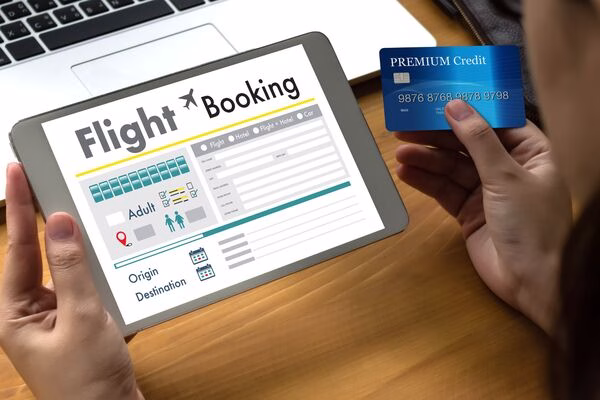 Person booking plane tickets online using tablet and credit card.