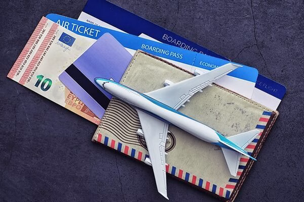 Plane tickets and boarding passes beside wallet and toy plane