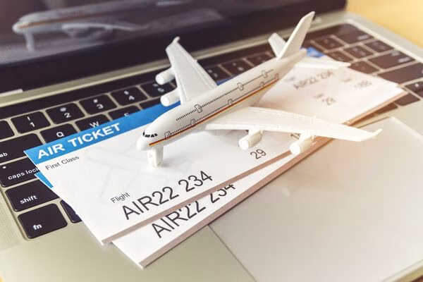 Billetes de avión y avión de juguete colocados en el teclado de una computadora portátil.
