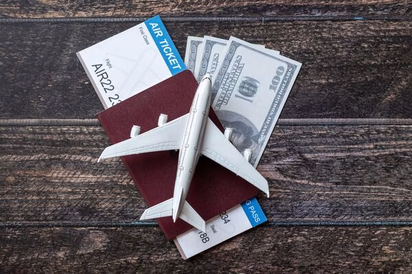 Billetes de avión con pasaporte, dinero en efectivo y un avión de juguete sobre la mesa.