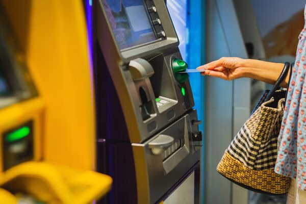 Woman inserts card into Bitcoin ATM at cash machine.
