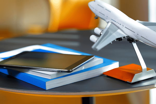 Modelo de avión con tableta y libros de viajes.
