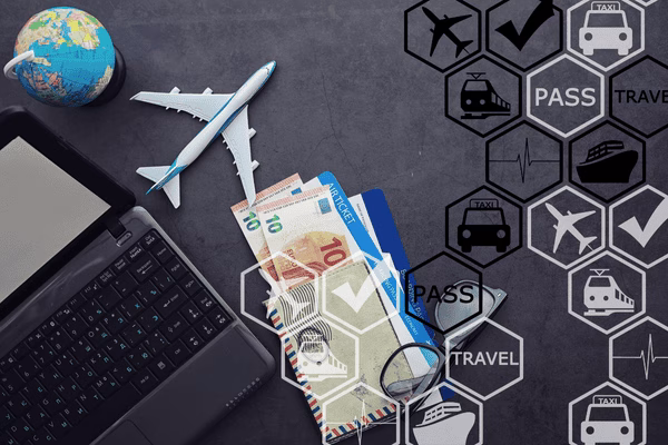 Billetes de avión y moneda junto a una computadora portátil