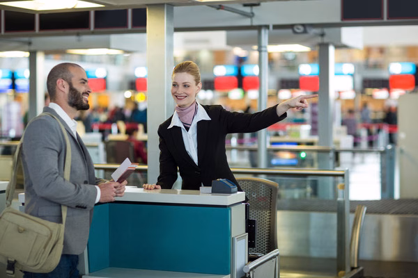 Personal de la aerolínea ayuda a un pasajero con los boletos de avión en el mostrador.
