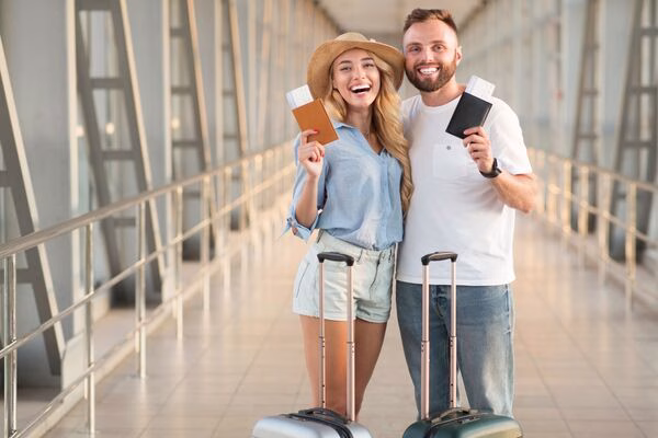 Happy couple at airport holding passports and plane tickets