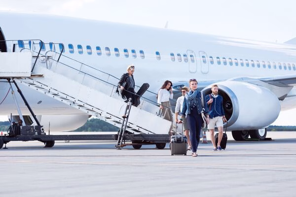 Viajeros que desembarcan del avión con equipaje y billetes de avión