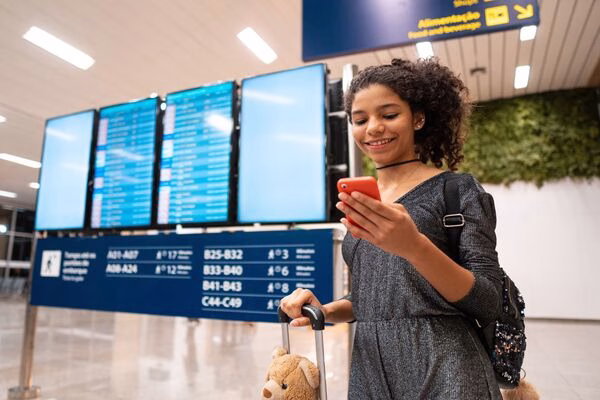 Un joven viajero revisa sus billetes de avión en su teléfono en el aeropuerto.
