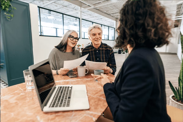 Clients Discussing Documents At Office Table
