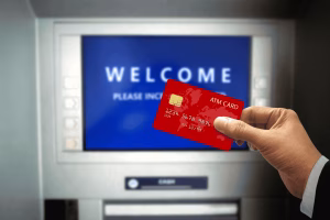 Mano sosteniendo una tarjeta cerca de un cajero automático de Bitcoin