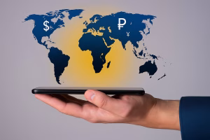 Mano sosteniendo un teléfono con símbolos de monedas globales
