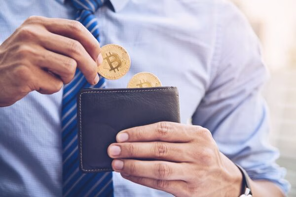  Hombre colocando Bitcoin en su billetera después de retirarlo de un cajero automático de Bitcoin
