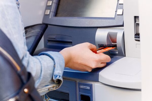 Person inserting card into Bitcoin ATM for crypto transaction.