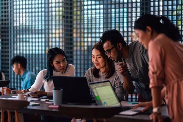 Equipo colaborando en la estrategia de pagos transfronterizos mediante computadoras portátiles