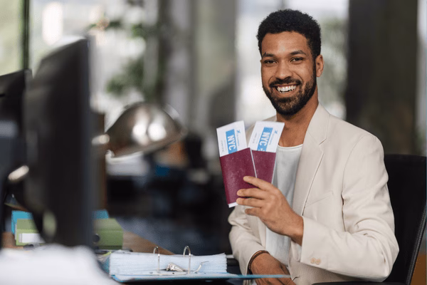 Business Traveler Showing His Plane Tickets At Desk
