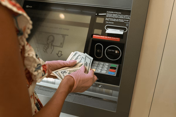 Persona contando efectivo antes de usar un cajero automático de Bitcoin
