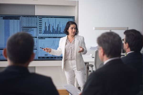 Mujer de negocios presenta datos de pagos transfronterizos a los miembros del equipo.