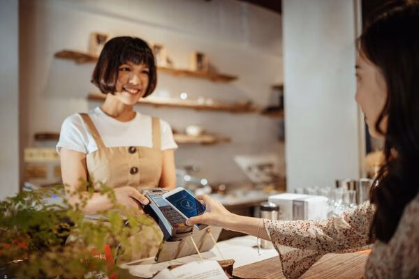 Cliente que usa el teléfono para pagos transfronterizos en una cafetería

