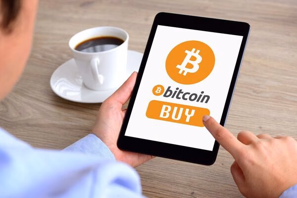  Persona que compra Bitcoin en una tableta después de visitar un cajero automático de Bitcoin
