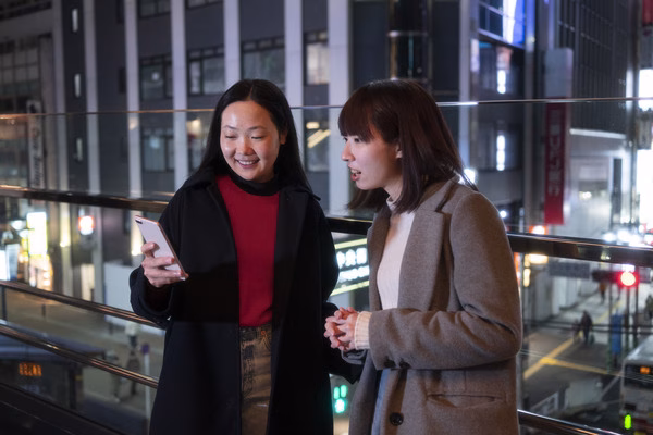 Two women discuss Cross Border Payments while using phone.