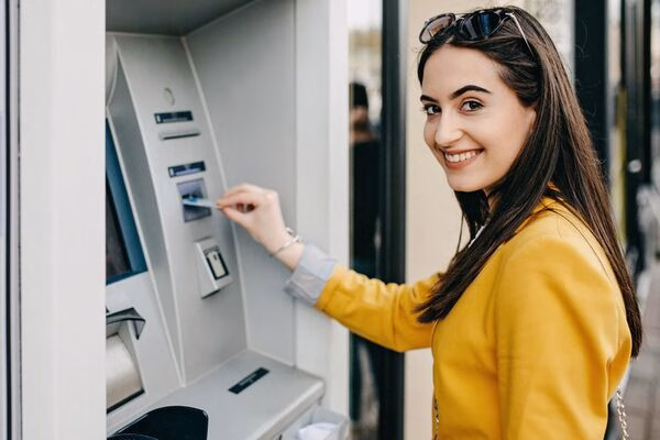 Un usuario inserta una tarjeta en un cajero automático de Bitcoin con una chaqueta amarilla.