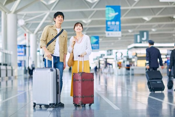 Couple at airport traveling with plane tickets and luggage.
