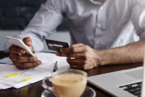 Un hombre realiza una transferencia de dinero en línea usando su teléfono inteligente y tarjeta