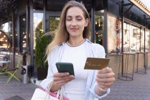 Mujer que usa un teléfono y una tarjeta para realizar pagos transfronterizos