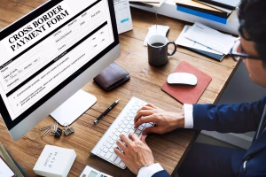 A man is typing Cross Border Payments details into a digital application form.