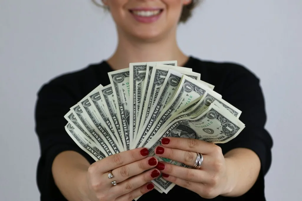A smiling woman holding cash for Money Transfer transaction.