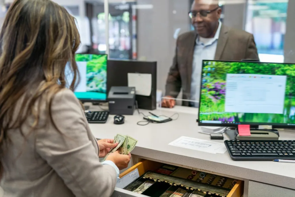 Bank teller counting cash for Money Transfer at service counter