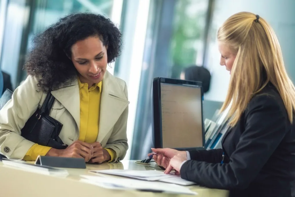 Customer discussing Money Transfer details with bank employee at desk.